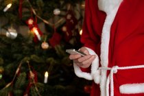 Санта Клаус с помощью мобильного телефона, обрезанный снимок — стоковое фото