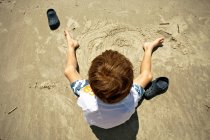 Хлопчик грає в пісок на пляжі — стокове фото