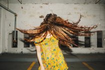 Vista frontal da jovem mulher tremendo seu longo cabelo ondulado no parque de estacionamento interior — Fotografia de Stock
