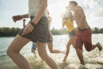 Gruppo di giovani amici che corrono nel lago — Foto stock