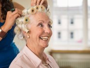 Mujer mayor con rodillos en peluquerías - foto de stock