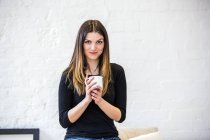 Retrato de bela jovem no apartamento segurando caneca de café — Fotografia de Stock