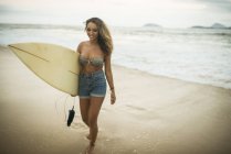 Young woman carrying surfboard on Ipanema Beach, Rio de Janeiro, Brazil — Stock Photo