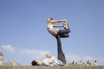 Man and woman practicing acrobatic yoga balance on wall — Stock Photo