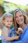 Porträt einer Mutter, die ihre kleine Tochter und ihren Hund hält — Stockfoto