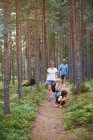 Padres caminando por el bosque con hijas - foto de stock