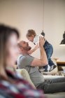 Pai levantando bebê menino cara a cara sorrindo — Fotografia de Stock