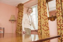 Portrait of senior woman standing at vintage home interior — Stock Photo