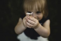 Mädchen hält Gänseblümchenblume lächelnd hoch — Stockfoto