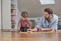 Father and son playing with wooden toy train set — Stock Photo