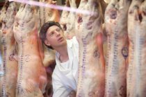 Carniceiro jovem do sexo masculino que inspeciona carne — Fotografia de Stock
