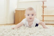 Portrait of smiling baby boy crawling on rug — Stock Photo