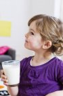 Menina segurando copo de leite em casa — Fotografia de Stock