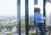 Hombre de negocios preocupado apoyado en la ventana de la oficina con Bruselas paisaje urbano, Bélgica - foto de stock