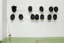 Máscaras de esgrima colgadas en la pared junto a la espada - foto de stock