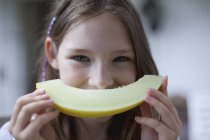 Retrato de niña con la cara sonriente rebanada de melón - foto de stock