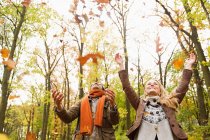 Smiling couple playing in autumn leaves — Stock Photo