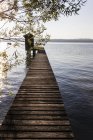 Diminishing perspective of wooden boathouse and pier at lake — Stock Photo