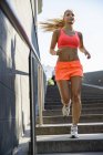 Young female runner moving down city stairway — Stock Photo
