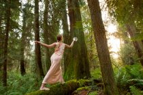 Reife Frau steht auf Baumstamm im Wald — Stockfoto