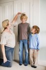 Мати вимірює своїх синів удома. — стокове фото