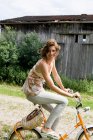 Femme à vélo sur la route rurale — Photo de stock