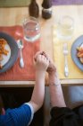 Бабушка и внук держатся за руки за обеденным столом — стоковое фото