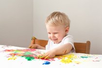 Мальчик играет с красками на пальцах — стоковое фото