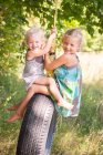 Девочка и сестра играют друг с другом на качелях — стоковое фото