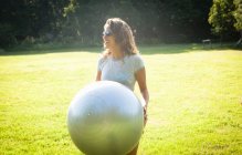Metà donna adulta tenendo palla esercizio in campo — Foto stock
