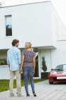 Couple devant la maison et voiture électrique — Photo de stock