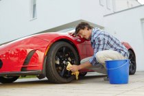 Hombre orgullosamente limpiando su coche eléctrico - foto de stock