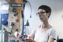 Woman in workshop looking at bicycle part — Stock Photo