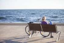 Mulher sênior desfrutando de vista para o mar no banco — Fotografia de Stock