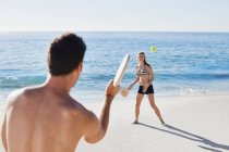 Пара, играющая в теннис на пляже — стоковое фото