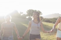 Three young females friends holding hands in sunlight — Stock Photo