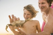 Pai e filho segurando caranguejo sorrindo — Fotografia de Stock