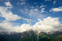 Vista di montagne lontane sotto il cielo nuvoloso blu — Foto stock