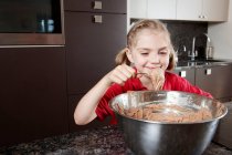 Girl eating cake mix from the bowl — Stock Photo