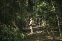 Женщина стоит в лесу и смотрит вверх — стоковое фото