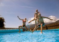 Дівчата і хлопчик стрибають в басейн — стокове фото