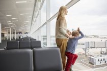 Mother and sons in departure lounge looking out of window, London, UK — Stock Photo