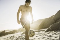 Mid adult man wearing swimming shorts playing soccer keepy uppy on beach, Cape Town, Afrique du Sud — Photo de stock