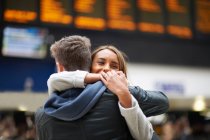 Heterosexual couple hugging at railway station, rear view — Stock Photo