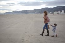 Мати і дочка тримають руки на пляжі — стокове фото