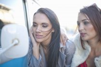 Two young adult female friends looking in camper van mirror — Stock Photo