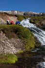 Hikers resting by waterfall, selective focus — Stock Photo