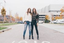Portrait of twin sisters, in urban area, standing side by side — Stock Photo