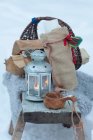 Basket with logs, candle lantern, wooden cup in snow — Stock Photo