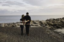 Молода пара стоїть біля моря, вид ззаду — стокове фото